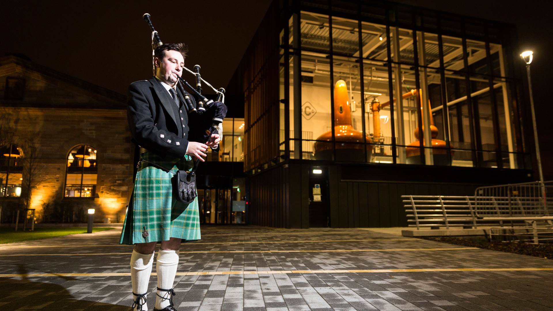 Scottish Piper outside The Clydeside Distillery welcoming evening guests
