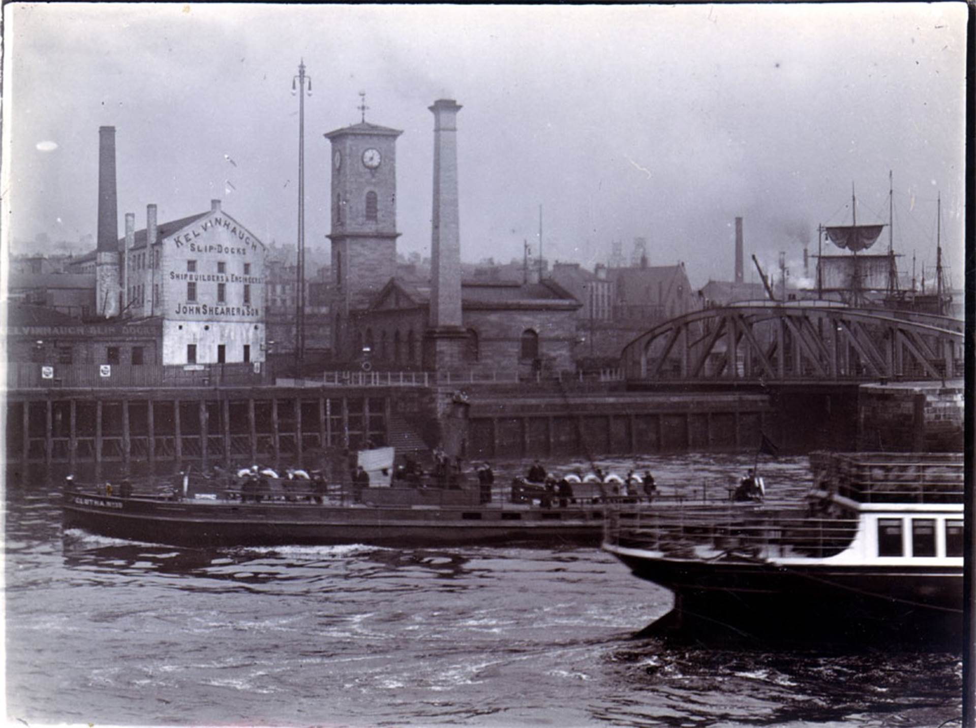 Old Clutha boats on the River Clyde passing the old Pumphouse building, which now houses the Clydeside Distillery