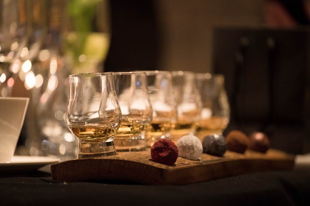 Wooden board of five whisky glasses, each with a different truffle chocolate