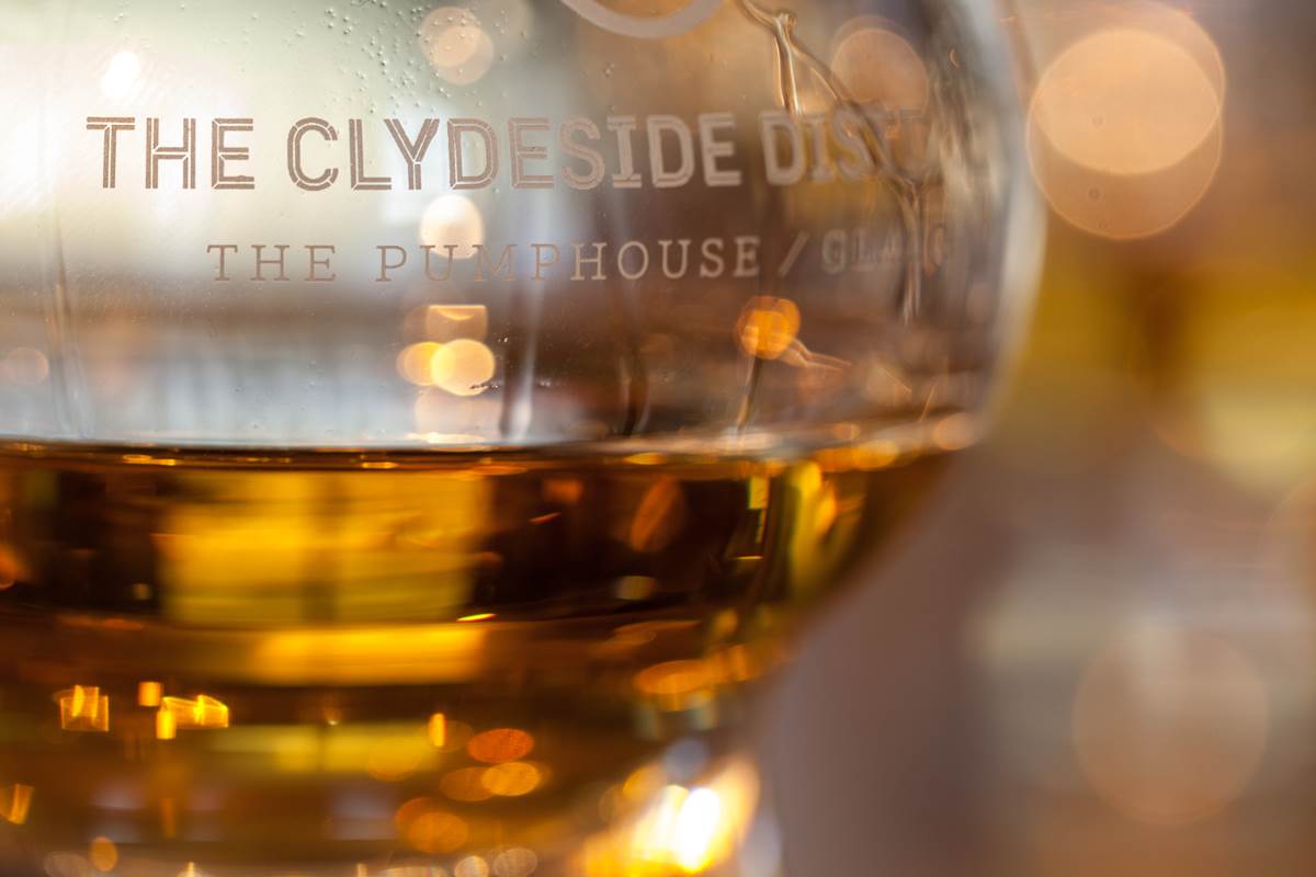 Dram of whisky in large, branded glass 